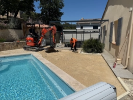 moquette de pierre posée à gréasque par viamenagement Excavatrice et ouvrier près d'une piscine.