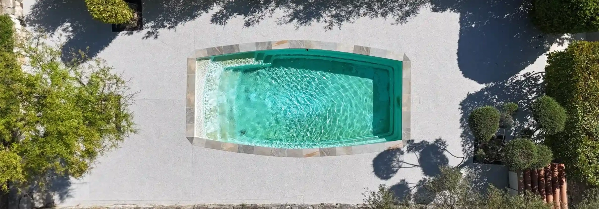Piscine rectangulaire vue d'en haut, entourée de végétation.