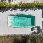 Piscine rectangulaire vue d'en haut, entourée de végétation.