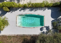 Piscine rectangulaire vue d'en haut, entourée de végétation.