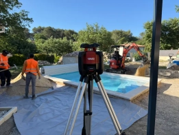 terrassement tour de piscine avant pose de moquette de pierre à gréasque par viamenagement – travaux en cours Chantier piscine avec niveau laser et ouvriers.